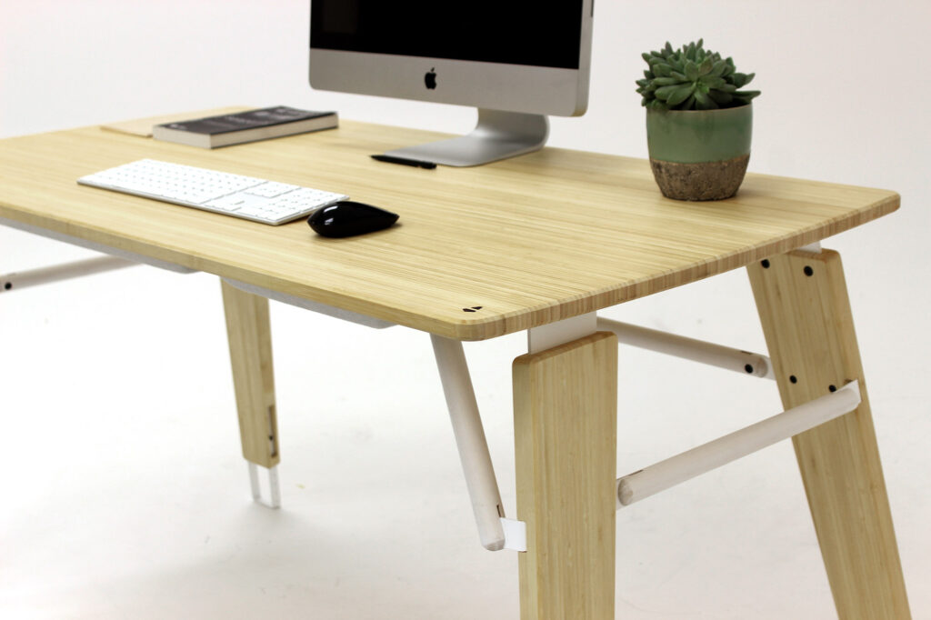 Artifact Desk Reduced A modern wooden desk by Evan Thomas of Product Design NZ features an iMac, keyboard, mouse, closed notebook, and a small potted succulent against a plain white background.