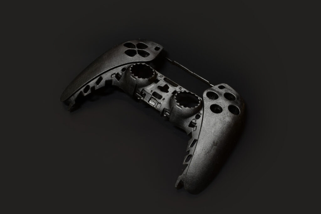 ET-ID Industrial Design 3D Print SLA FDM A disassembled black video game controller shell, missing buttons and internal components, is displayed on a dark background—an example of Industrial Design NZ with an emphasis on Design for Manufacture.
